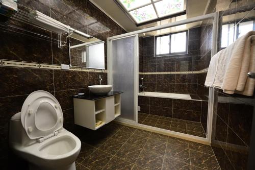 a bathroom with a toilet and a shower and a sink at De Mei Homestay in Qimei