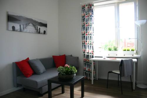 Baltica Apartament في غدانسك: غرفة معيشة مع أريكة وطاولة مع وسائد حمراء