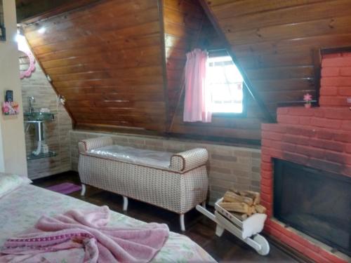 a bedroom with a fireplace and a bed and a chair at Chales Alpes Germanicos in Monte Verde