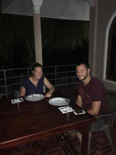 two men sitting at a table at a restaurant at New Land Guest House in Pasikuda
