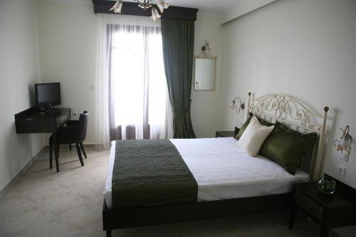 a bedroom with a bed and a desk and a window at Makedos Sea View in Nea Vrasna