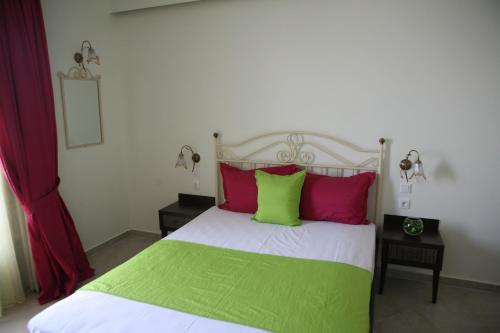 a bedroom with a bed with red and green pillows at Makedos Sea View in Nea Vrasna