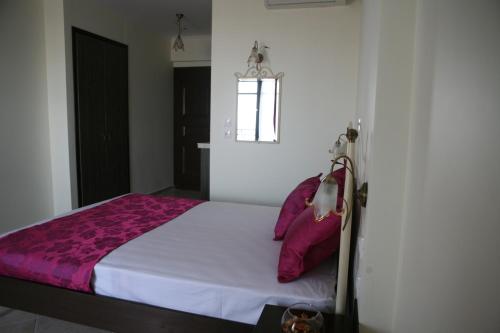 a bedroom with a bed with pink pillows at Makedos Sea View in Nea Vrasna