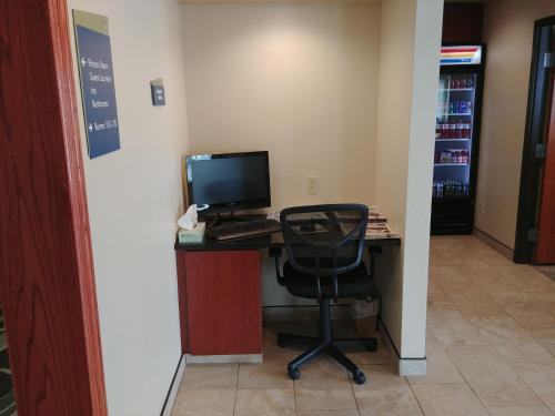 a desk with a computer monitor and a chair at Boarders Inn & Suites by Cobblestone Hotels - Broken Bow in Broken Bow