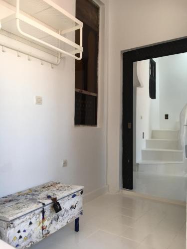 um quarto branco com um banco em frente a uma porta em Dar Said em Asilah