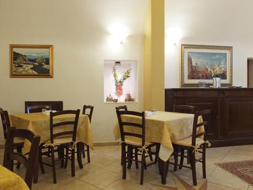 a dining room with tables and chairs and paintings at Villa Musica in Sannicola