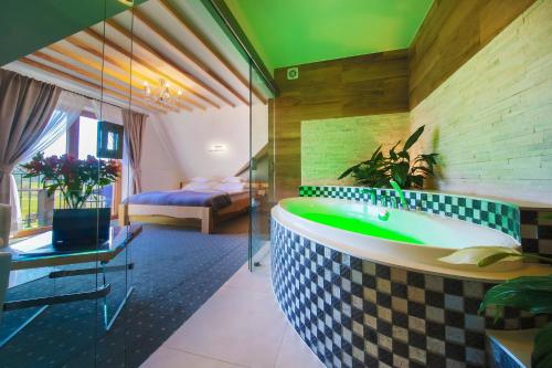 a bathroom with a bath tub and a bedroom at ECO Villa Grand Karpatia Ski&Spa in Murzasichle