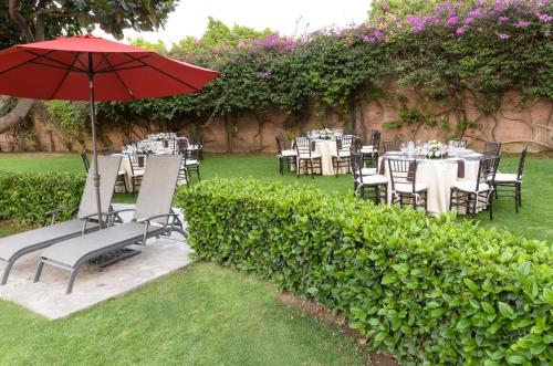 a garden with tables and chairs with an umbrella at Hotel San Francisco Leon in León