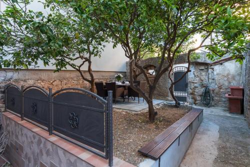 a wooden bench in a garden with a tree at Riva Suite 1 in Komiža
