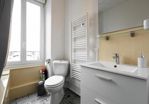 une salle de bain avec toilettes, lavabo et fenêtre dans l'établissement Le duc de Vichy, à Vichy