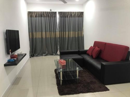 a living room with a black couch and a glass table at Mr.J Homestay in Taiping