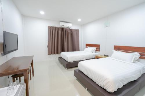 a bedroom with two beds and a desk and a television at Myrrh Hotel Chanthaburi in Chanthaburi
