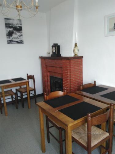 a dining room with two tables and a fireplace at Les Greniers De Blanche in Le Vivier-sur-Mer