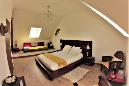 a bedroom with a large bed and a chair at La Closeraie in Noyers-sur-Cher