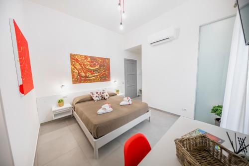 a white bedroom with a bed and a red chair at Pepito palace in Cefalù