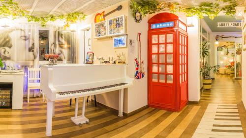 een kamer met een witte piano en een rode telefooncel bij Pousada Piano Piano in Campos do Jordão