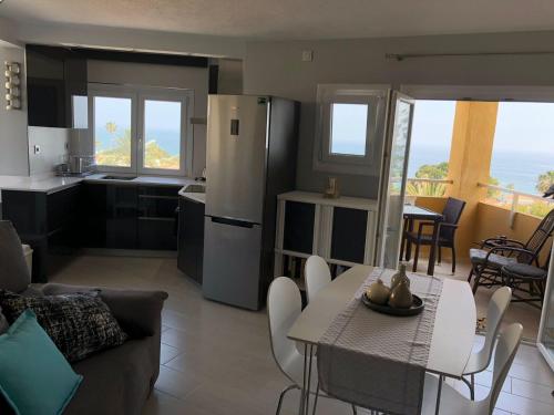ラ・カラ・デ・ミハスにあるLa Cala de Mijas Sea View Apartment Walking to the Beachのキッチン、リビングルーム(テーブル、椅子付)