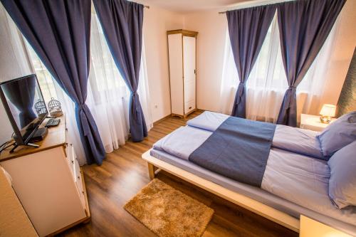 a bedroom with blue curtains and a bed with a television at Heaven in Sălişte