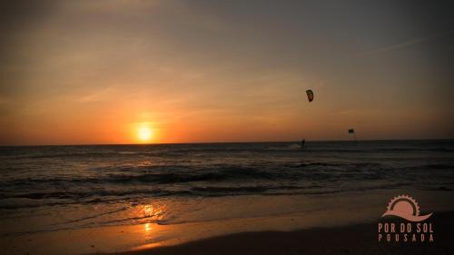 a person flying a kite on the beach at sunset at Pousada Por do Sol in Jericoacoara