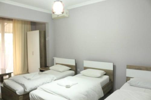 a room with three beds with white sheets at Old Street Guesthouse in Batumi