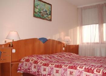 a bedroom with a bed with a red and white blanket at Hotel Napsugar in Hévíz