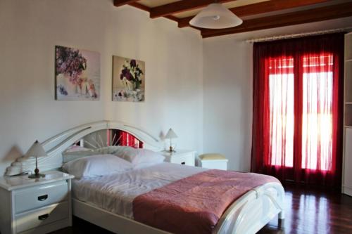1 dormitorio con 1 cama y una ventana con cortinas rojas en Villa Antonia en Giannádes