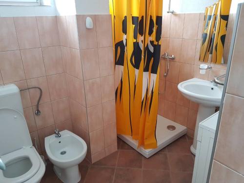 a bathroom with a shower curtain with a toilet and a sink at Roses in Bihać