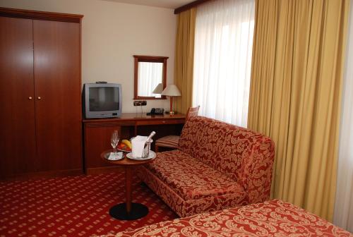 um quarto de hotel com um sofá e uma televisão em Hotel Zvezda em Murska Sobota