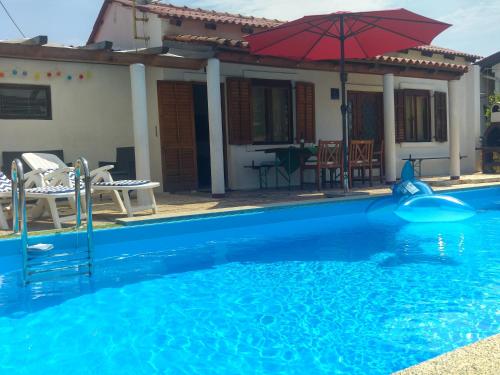 a swimming pool in front of a house with an umbrella at Holiday Home ZEN in Fažana