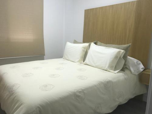 een bed met witte lakens en kussens in een kamer bij Piso en la playa de Sanlucar in Sanlúcar de Barrameda
