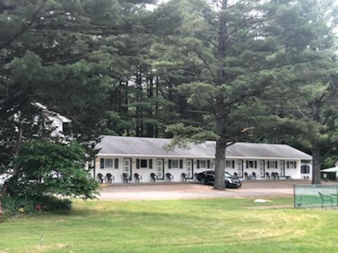 a white building with a tree in front of it at Catskill Motor Court in Catskill