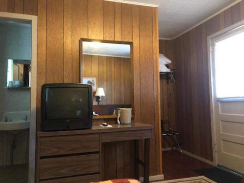 a room with a television on a dresser with a mirror at Catskill Motor Court in Catskill