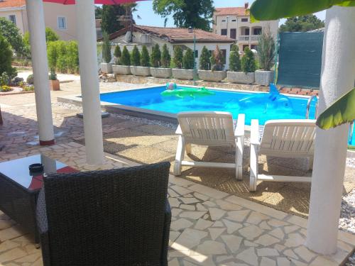 a swimming pool with two chairs and a table and an umbrella at Holiday Home ZEN in Fažana