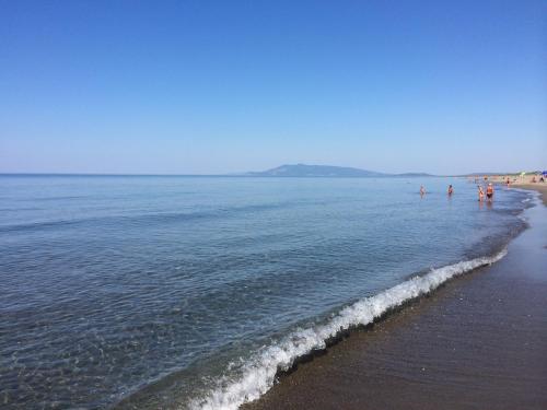 a group of people standing in the water at the beach at Hotel Residence I Briganti di Capalbio in Capalbio
