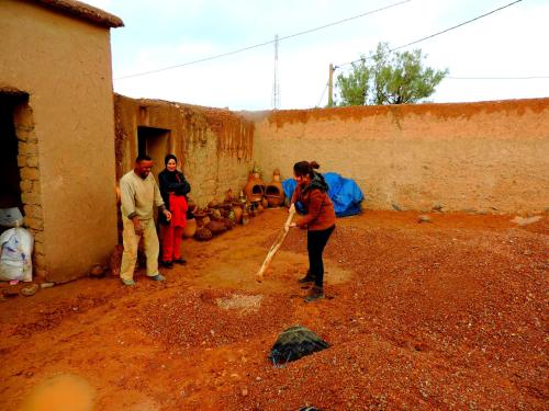 a woman holding a baseball bat in front of a building at Auberge Migusta in Skoura