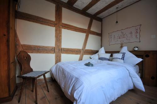 a bedroom with a white bed and a chair at La Maison 1603 in Hunawihr