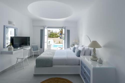 1 dormitorio blanco con 1 cama y TV en Antoperla Luxury Hotel & Spa, en Perissa