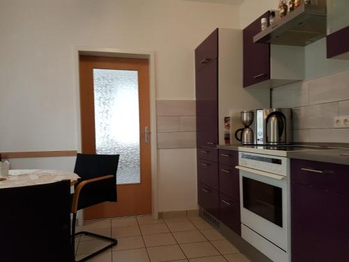 une cuisine avec des placards violets, une table et une cuisinière dans l'établissement Ferienoase, à Pirna