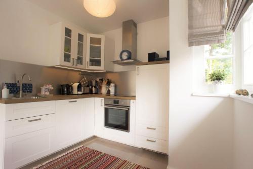 a kitchen with white cabinets and a window at Claras Strandhuus in Zingst