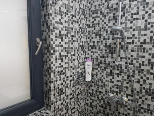 a shower in a bathroom with black and white tiles at Holiday Apartment Mamaia Nord in Mamaia Nord