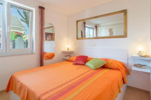 a bedroom with an orange bed with a mirror at Apartments Kiara Sabunike 836 in Privlaka