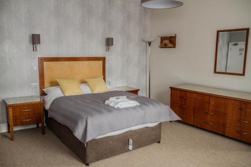 a bedroom with a bed and two dressers and a mirror at Keld Green House in Seascale