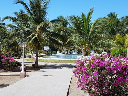 a walkway in a resort with palm trees and flowers at Safari Village Saly V 225 in Saly Portudal