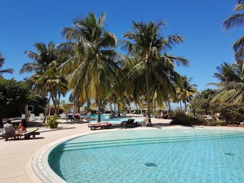 a swimming pool with palm trees in a resort at Safari Village Saly V 225 in Saly Portudal