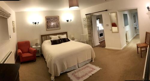 ブラックリーにあるTroy's Barnのベッドルーム1室(大型ベッド1台、赤い椅子付)