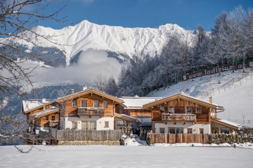 a log cabin in the snow with a snow covered mountain at Hüttendorf Ladizium in Ladis