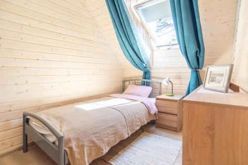 een kleine slaapkamer met een bed en een raam bij Hubertus Pogorzelica - domki przy plaży in Pogorzelica