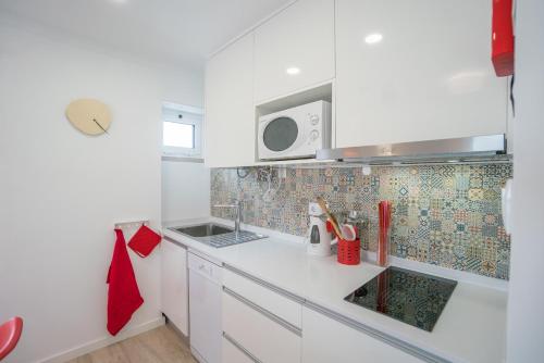 a white kitchen with a sink and a microwave at Casas da Avó II in Santa Cruz