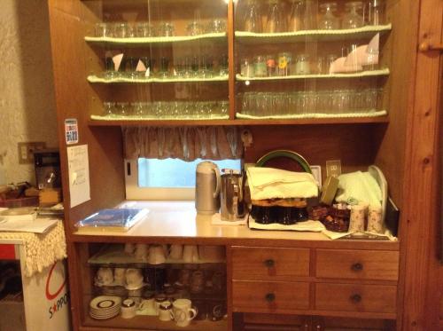 uma cozinha com um balcão e um armário com copos em Pension Roku em Hakuba