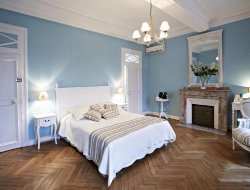een blauwe slaapkamer met een bed en een open haard bij Maison d'hôtes "Les Jardins de Mazamet" in Mazamet